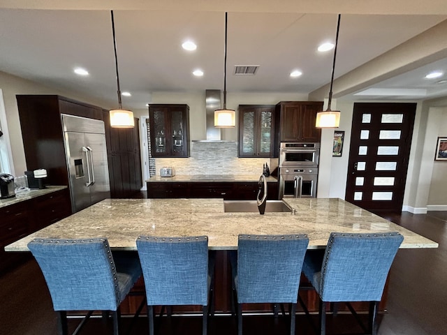 78-106 Holuakai St, Kailua-Kona, HI 96740 - kitchen with built in fridge, wall chimney range hood, stainless steel double oven, tasteful backsplash, and glass insert cabinets