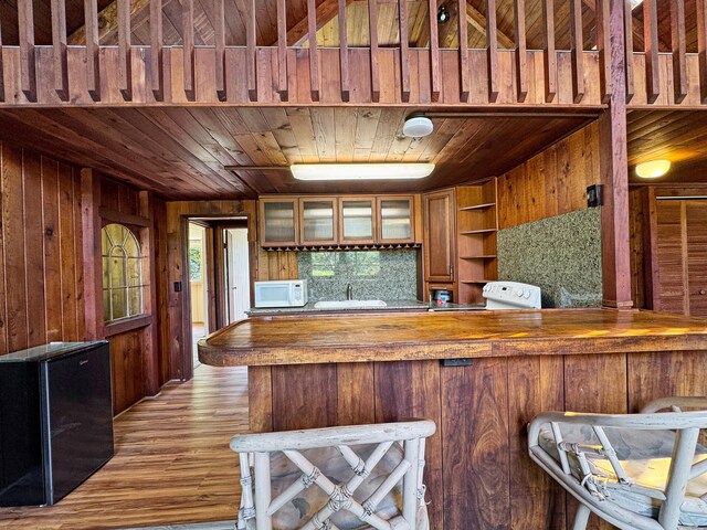 94-2664 Lorenzo Rd, Naalehu, HI 96772 - kitchen featuring wooden ceiling, wooden walls, brown cabinets, glass insert cabinets, and butcher block countertops