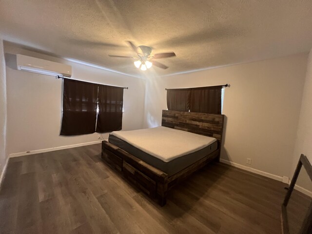 15-1509 22nd Ave, Keaau, HI 96749 - bedroom with a wall mounted air conditioner, a textured ceiling, dark wood-style floors, baseboards, and a ceiling fan