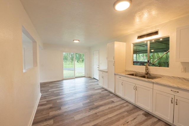 15-2746 Lai St, Pahoa, HI 96778 - kitchen with a sink, light wood-style flooring, white cabinetry, light stone counters, and baseboards