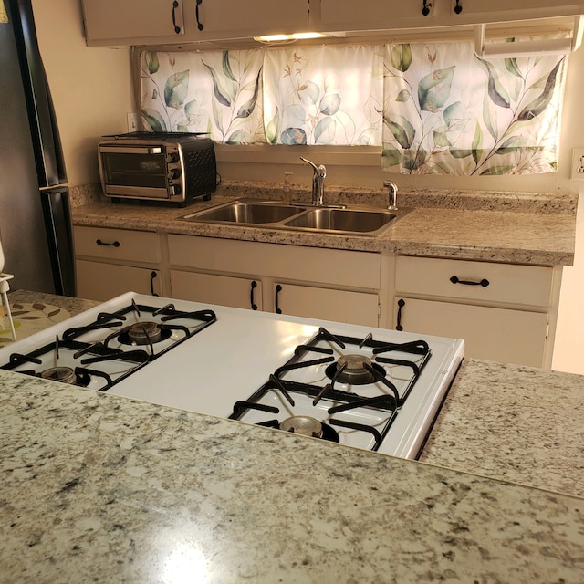 75-5724 Alahou St Unit 202A, Kailua-Kona, HI 96740 - kitchen featuring a sink, freestanding refrigerator, light countertops, white cabinets, and gas range
