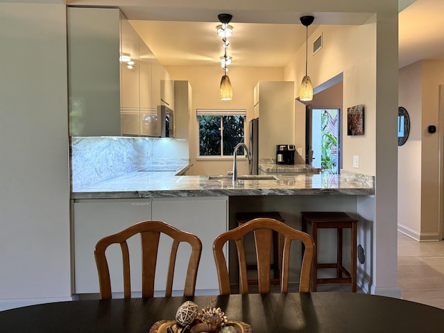 69-1010 Keana Pl Unit B101, Waikoloa, HI 96738 - kitchen with a sink, a peninsula, hanging light fixtures, stone countertops, and a kitchen breakfast bar