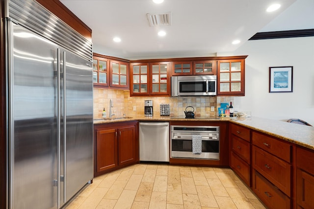4-820 Kuhio Hwy Unit A101, Kapaa, HI 96746 - kitchen with appliances with stainless steel finishes, backsplash, a sink, glass insert cabinets, and light stone counters