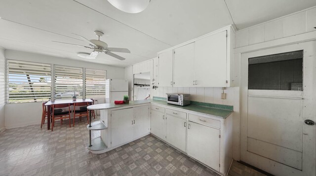 267 Hookipa Rd, Kapaa, HI 96746 - kitchen with freestanding refrigerator, tile patterned floors, a ceiling fan, a peninsula, and white cabinetry