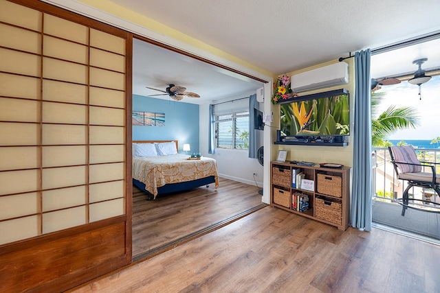 75-5766 Kuakini Hwy Unit 503, Kailua-Kona, HI 96740 - bedroom with an AC wall unit, wood finished floors, access to outside, baseboards, and ceiling fan