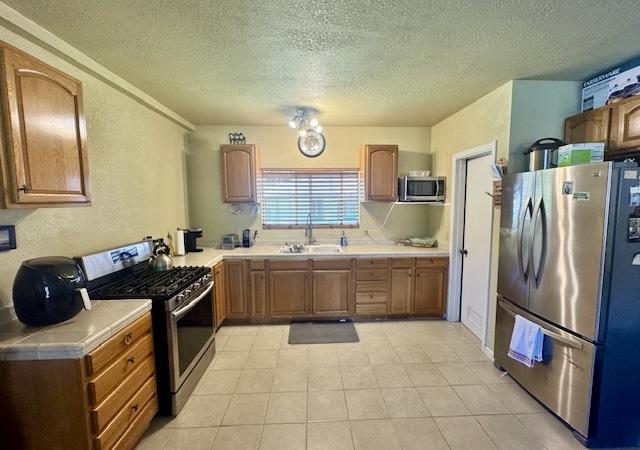 15-2690 Mahimahi St, Pahoa, HI 96778 - kitchen with stainless steel appliances, a sink, a textured ceiling, brown cabinetry, and light tile patterned floors