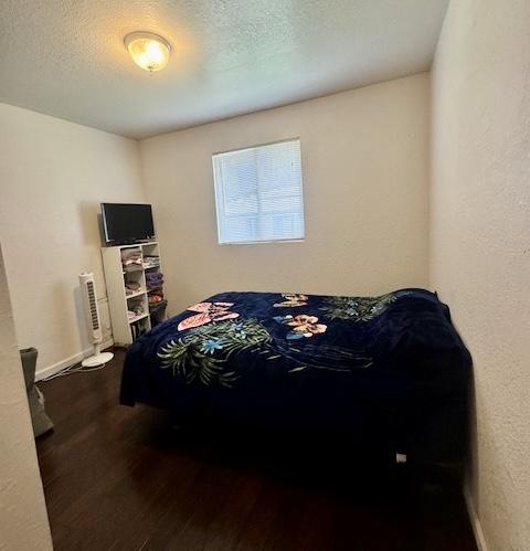 15-2690 Mahimahi St, Pahoa, HI 96778 - bedroom with dark wood finished floors, a textured ceiling, baseboards, and a textured wall