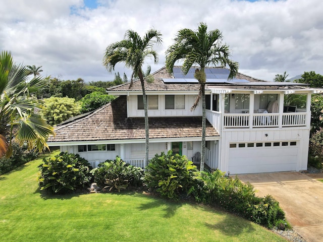 5359 Pau A Laka St, Koloa, HI 96756 - view of front of house with a front yard, board and batten siding, roof mounted solar panels, driveway, and a garage