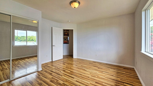 94-6663 Kamaoa Rd, Naalehu, HI 96772 - unfurnished bedroom featuring multiple windows, wood finished floors, baseboards, and a closet