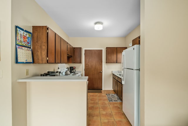 4720 Menehune Rd, Waimea, HI 96796 - kitchen featuring freestanding refrigerator, a peninsula, light tile patterned floors, light countertops, and brown cabinetry