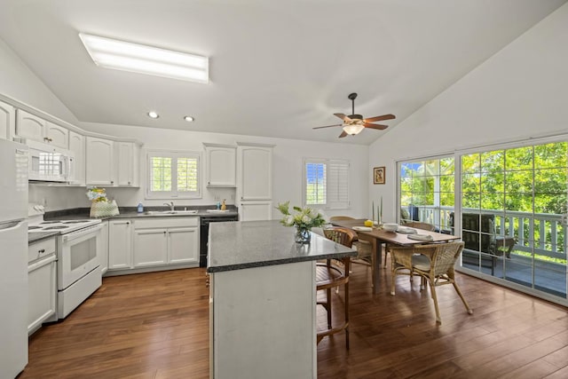 15-1663 Beach Rd, Keaau, HI 96749 - kitchen featuring white appliances, a sink, a breakfast bar area, a center island, and dark wood-style flooring