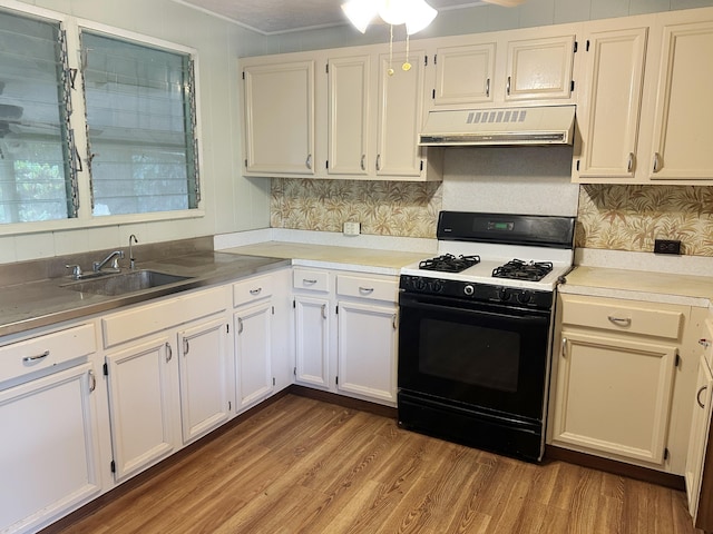 4854 Aliali Rd, Kapaa, HI 96746 - kitchen with ventilation hood, black range with gas stovetop, a sink, wood finished floors, and white cabinets