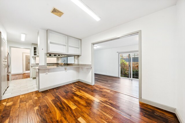 2969 Aloalo Pl, Lihue, HI 96766 - kitchen with hardwood / wood-style flooring, a kitchen breakfast bar, light stone countertops, white cabinetry, and a peninsula
