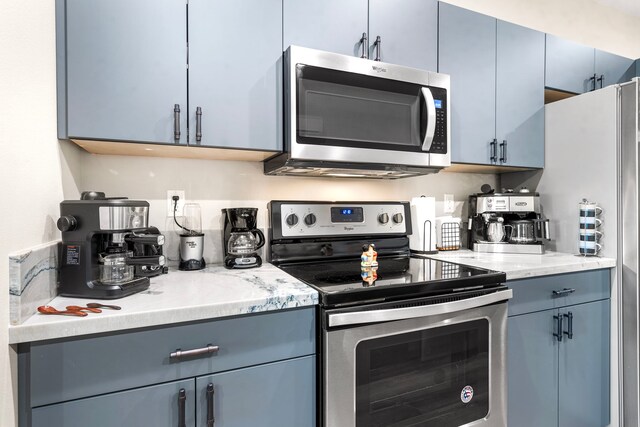 75-5726 Lamaokeola St, Kailua-Kona, HI 96740 - kitchen featuring appliances with stainless steel finishes, gray cabinetry, blue cabinetry, and light stone countertops