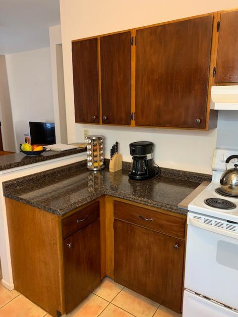 4724 Menehune Rd, Waimea, HI 96796 - kitchen with white electric stove, extractor fan, light tile patterned flooring, and a peninsula