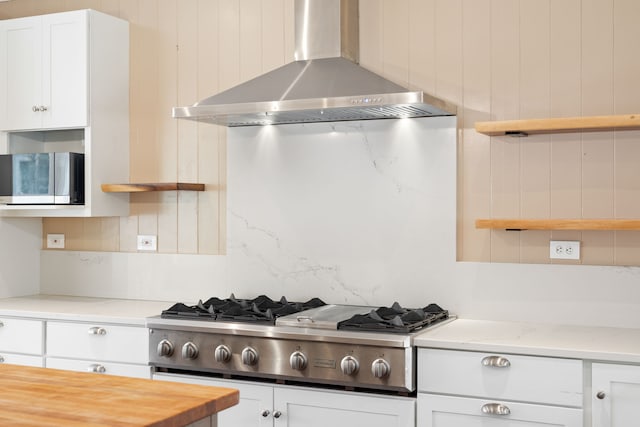 3018 Poipu Rd, Koloa, HI 96756 - kitchen featuring wall chimney range hood, appliances with stainless steel finishes, decorative backsplash, white cabinetry, and light stone countertops