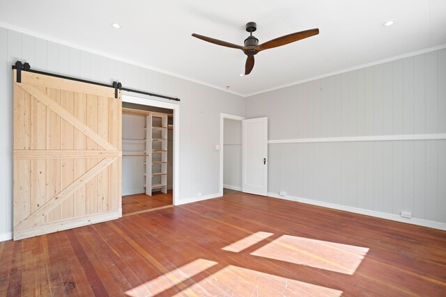 3018 Poipu Rd, Koloa, HI 96756 - unfurnished bedroom featuring hardwood / wood-style flooring, a barn door, baseboards, crown molding, and ceiling fan