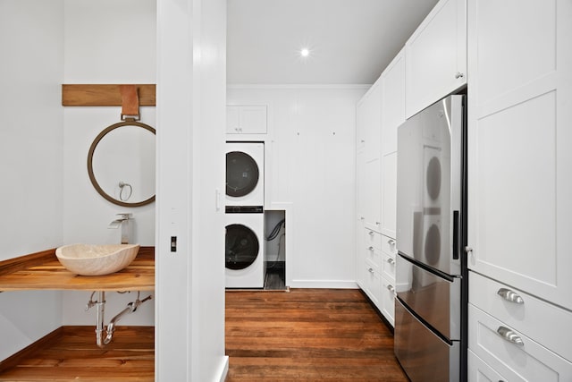 3018 Poipu Rd, Koloa, HI 96756 - laundry room with stacked washer and clothes dryer, dark wood-type flooring, crown molding, and baseboards