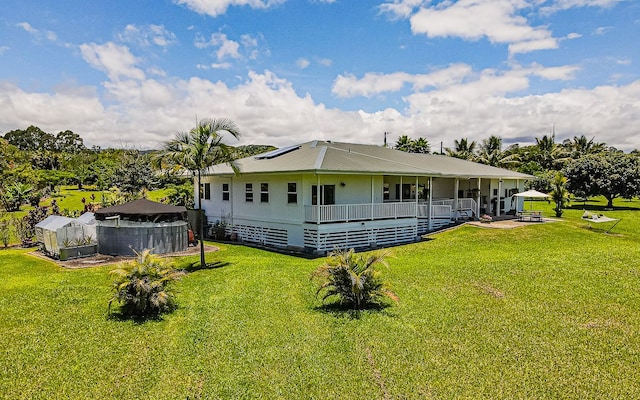 28-387 Kulaimano Rd, Pepeekeo, HI 96783 - view of front facade with roof mounted solar panels, a front lawn, and covered porch