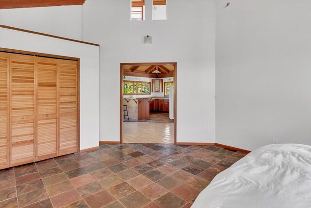 12-7158 Loke Pl, Pahoa, HI 96778 - unfurnished bedroom with stone tile flooring, a towering ceiling, baseboards, and a closet