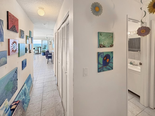 77-6311 Alii Dr Unit 306, Kailua-Kona, HI 96740 - hallway with light tile patterned floors, a textured ceiling, and a sink