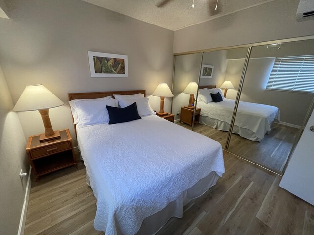 75-5719 Alii Dr Unit 409, Kailua-Kona, HI 96740 - bedroom featuring a closet, wood finished floors, a wall unit AC, and baseboards