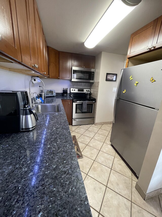 75-5719 Alii Dr Unit 409, Kailua-Kona, HI 96740 - kitchen with appliances with stainless steel finishes, a sink, light tile patterned flooring, dark stone countertops, and tasteful backsplash