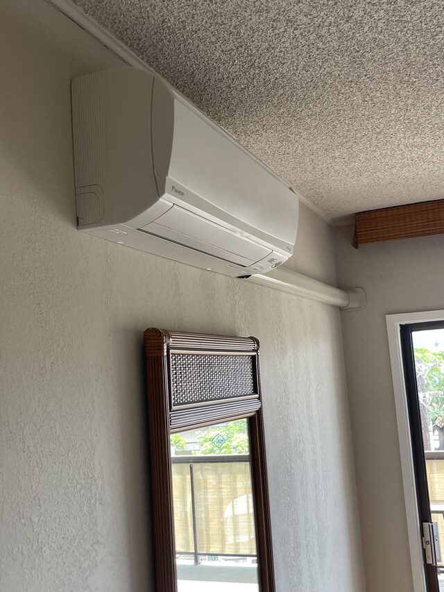 75-5719 Alii Dr Unit 409, Kailua-Kona, HI 96740 - detailed view of a wall mounted AC, a textured wall, and a textured ceiling