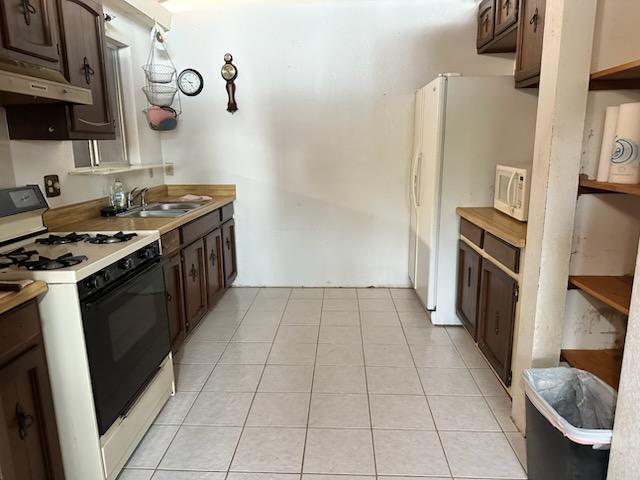 74-5087 Kumakani St, Kailua-Kona, HI 96740 - kitchen featuring gas stove, under cabinet range hood, dark brown cabinetry, a sink, and light tile patterned floors