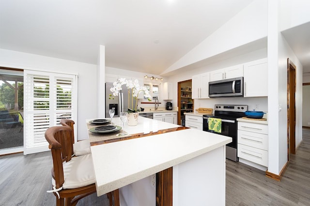 15-2063 18th Ave, Keaau, HI 96749 - kitchen with appliances with stainless steel finishes, lofted ceiling, white cabinets, light wood finished floors, and a breakfast bar