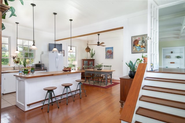 39-3383 Old Mamalahoa Hwy, Ookala, HI 96774 - kitchen with freestanding refrigerator, wooden counters, light wood-style floors, white cabinetry, and pendant lighting