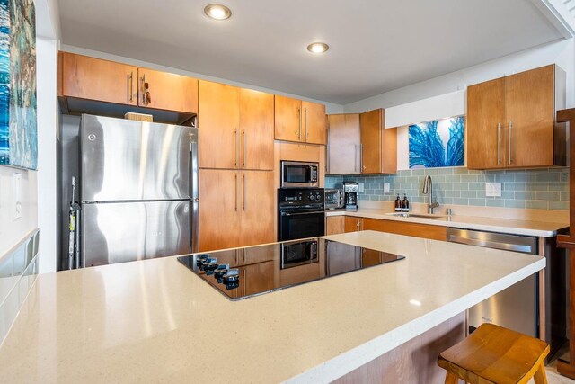3880 Wyllie Rd Unit 12B, Princeville, HI 96722 - kitchen featuring black appliances, a sink, tasteful backsplash, a breakfast bar area, and brown cabinetry