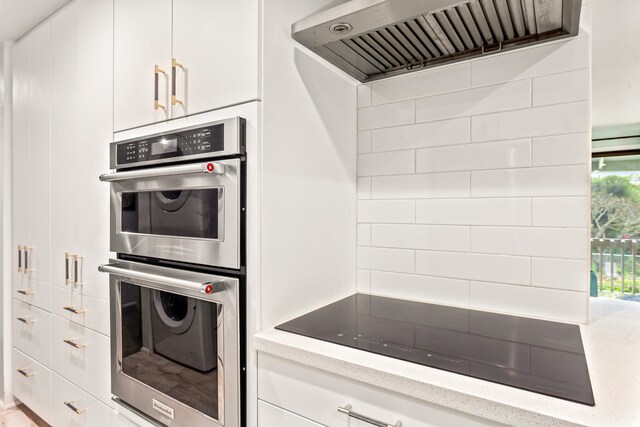 3057 Poipu Rd Unit C10, Koloa, HI 96756 - kitchen with double oven, black electric stovetop, ventilation hood, white cabinets, and light stone counters