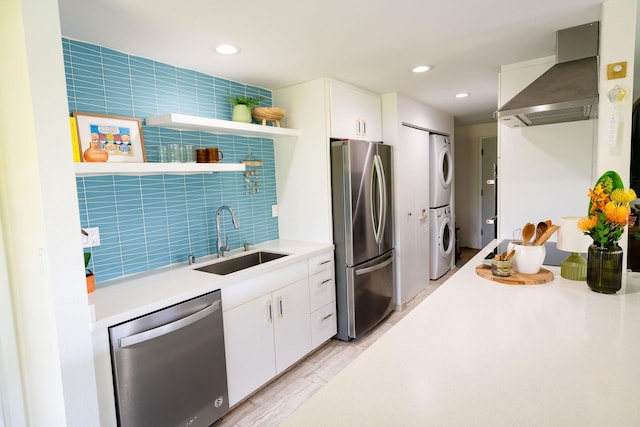 3057 Poipu Rd Unit C10, Koloa, HI 96756 - kitchen with appliances with stainless steel finishes, wall chimney range hood, estacked washer and dryer, a sink, and white cabinetry