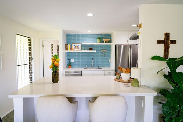 3057 Poipu Rd Unit C10, Koloa, HI 96756 - kitchen featuring appliances with stainless steel finishes, a sink, white cabinets, open shelves, and a kitchen bar