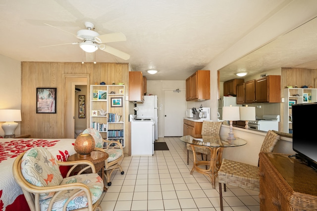 5061 Lawai Rd Unit 333, Koloa, HI 96756 - kitchen featuring light tile patterned floors, a ceiling fan, brown cabinetry, wooden walls, and washer / clothes dryer