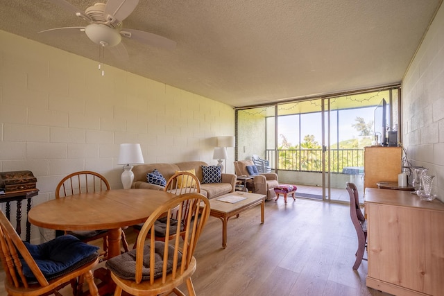 1875 Kalanianaole Ave Unit 409, Hilo, HI 96720 - dining area featuring light wood-style flooring, a textured ceiling, concrete block wall, a ceiling fan, and floor to ceiling windows
