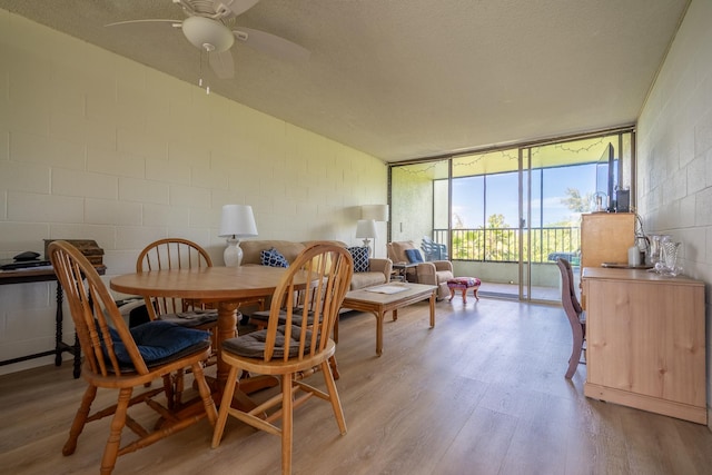 1875 Kalanianaole Ave Unit 409, Hilo, HI 96720 - dining room with light wood-style flooring, concrete block wall, ceiling fan, and a wall of windows