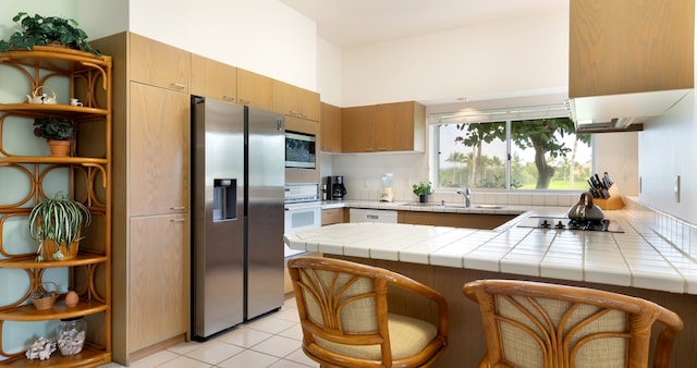69-1010 Keana Pl Unit F105, Waikoloa, HI 96738 - kitchen featuring appliances with stainless steel finishes, a peninsula, a sink, open shelves, and tile counters