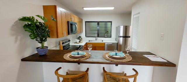 77-305 Kalani Way Unit 6, Kailua-Kona, HI 96740 - kitchen with appliances with stainless steel finishes, a sink, a peninsula, and a breakfast bar