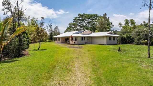15-2060 29th Ave, Keaau, HI 96749 - back of house featuring an attached garage, solar panels, a lawn, and driveway
