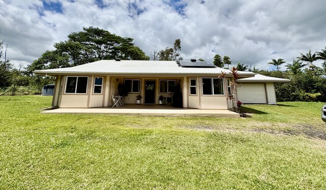 15-2060 29th Ave, Keaau, HI 96749 - back of property featuring an attached garage, roof mounted solar panels, and a yard