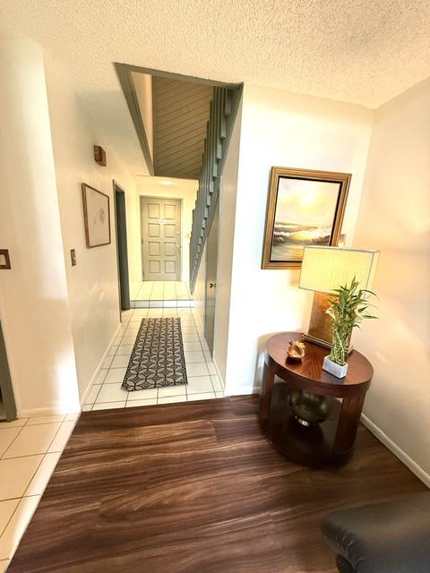 3880 Wyllie Rd Unit 8C, Princeville, HI 96722 - hall with tile patterned flooring, a textured ceiling, and baseboards