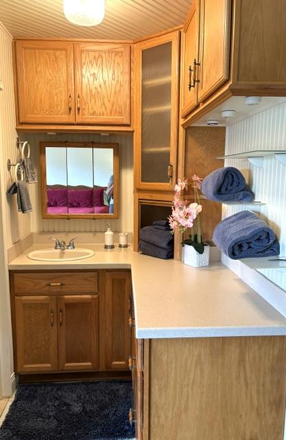 3880 Wyllie Rd Unit 8C, Princeville, HI 96722 - kitchen with a sink, light countertops, glass insert cabinets, and brown cabinetry