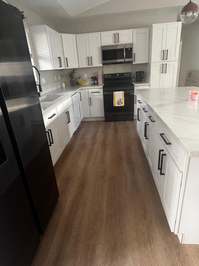 16-2062 Paradise Dr, Pahoa, HI 96778 - kitchen with stainless steel microwave, black electric range oven, dark wood finished floors, white cabinets, and light stone counters