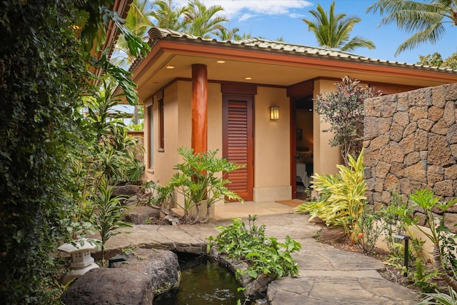 68-108 Pukaua Pl, Kamuela, HI 96743 - doorway to property with stucco siding, a small pond, and a tiled roof