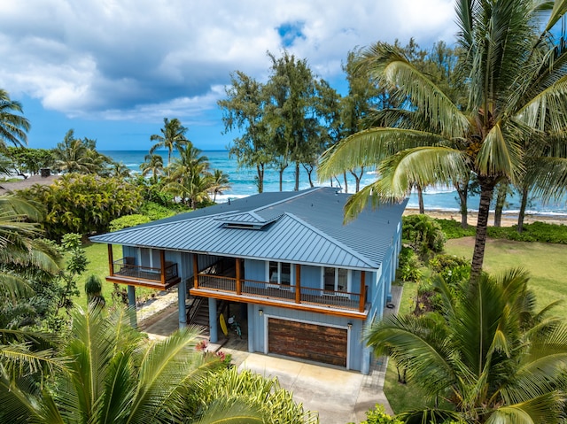 7312 Alealea Rd, Hanalei, HI 96722 - coastal inspired home with metal roof, a water view, concrete driveway, an attached garage, and stairs