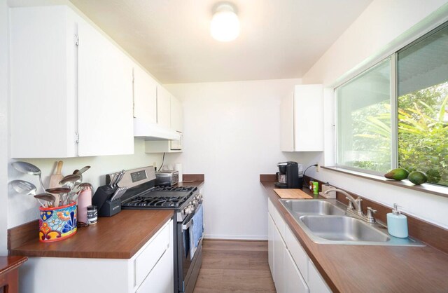 15-1893 32nd Ave, Keaau, HI 96749 - kitchen featuring stainless steel gas stove, under cabinet range hood, light wood-style floors, a sink, and white cabinets