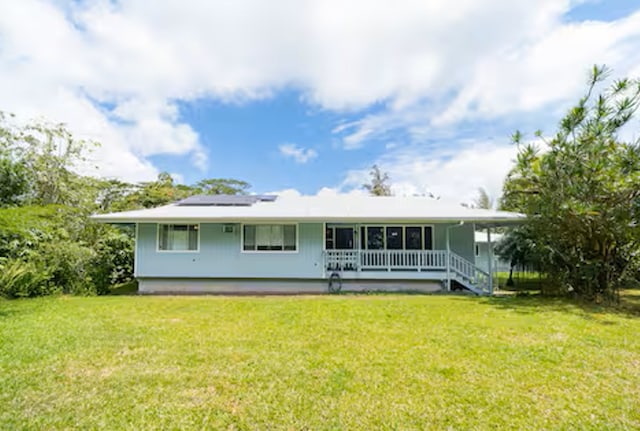 15-1893 32nd Ave, Keaau, HI 96749 - back of property featuring roof mounted solar panels, a lawn, and covered porch