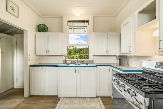 2819 Kapena St, Lihue, HI 96766 - kitchen with stainless steel range with gas stovetop, a sink, white cabinetry, light countertops, and light wood-type flooring
